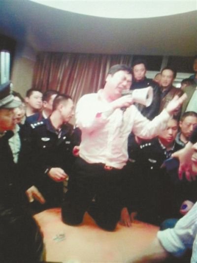 4月19日,泰州市濱江工業園區管委會招待中心,一男子跪在酒桌上喊話求饒。李根 攝