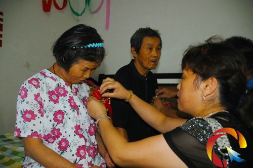 錦屏縣民政局黨組書記楊從立給新娘吳朝芝佩戴胸花